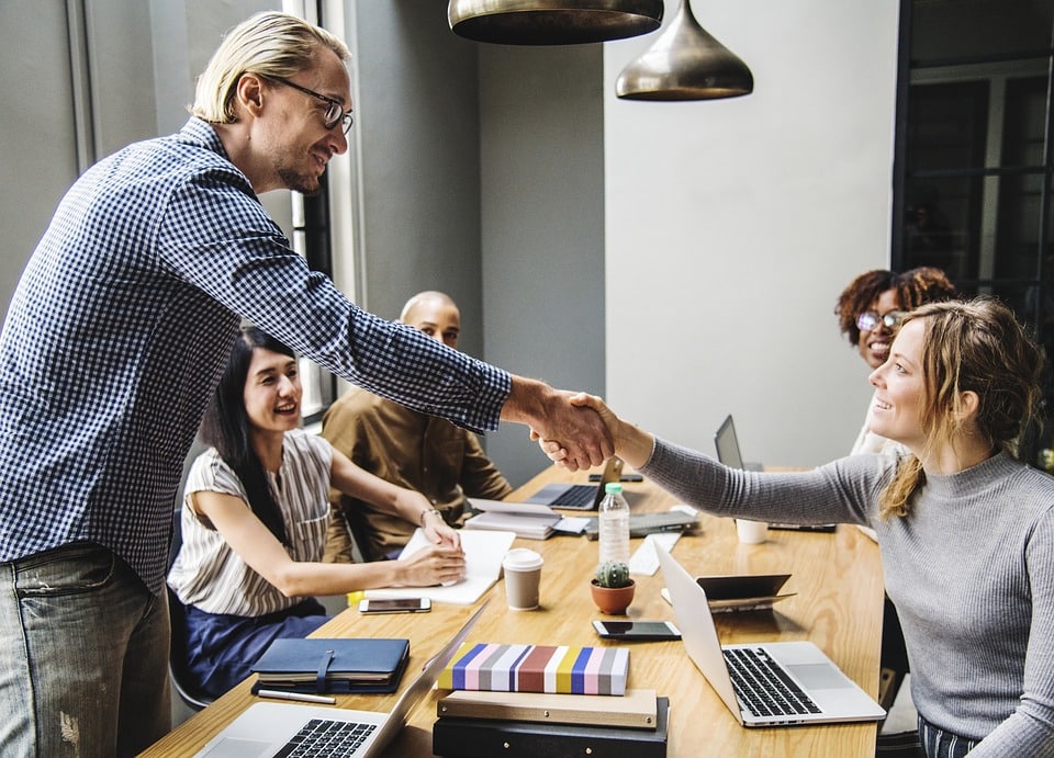 Man and woman shaking hands in an office, highlighting a successful agreement or partnership.