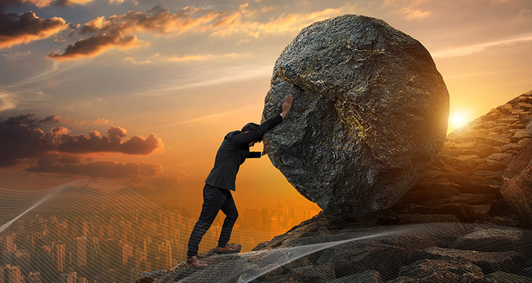 man pushing a boulder up a mountain
