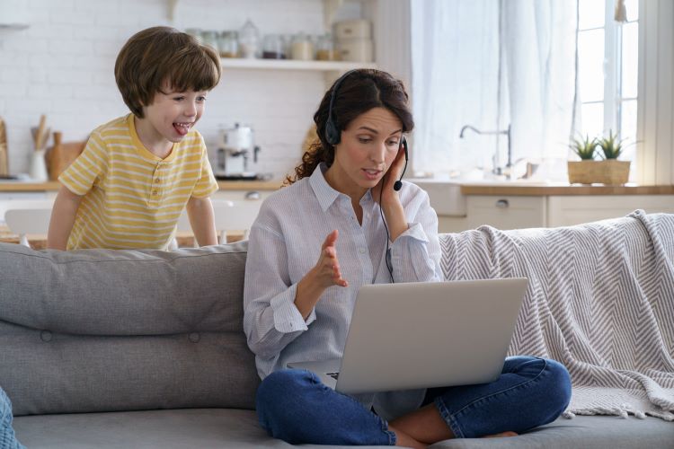 woman working from home and having a conference call but her kid is behind her