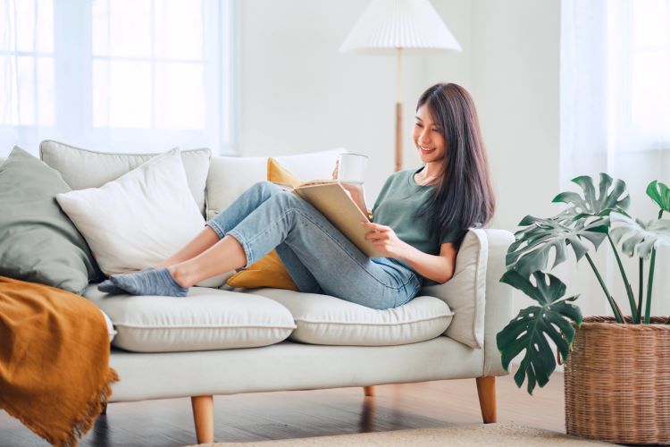 woman lounging in a sofa while reading a book