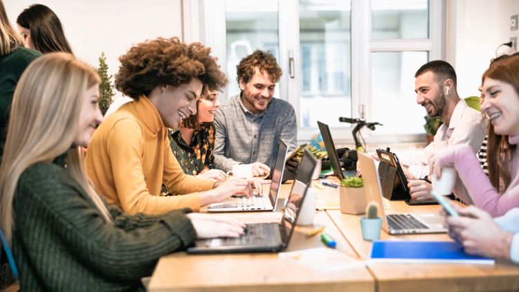 employees gathered at one table and working on their laptops 