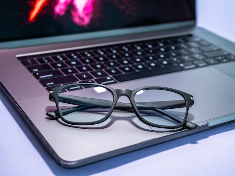 Blue light blocking glasses on the laptop. Black frame glasses for filtering blue light from the computer. Prevent Computer Vision Syndrome. Eye protection from PC screen