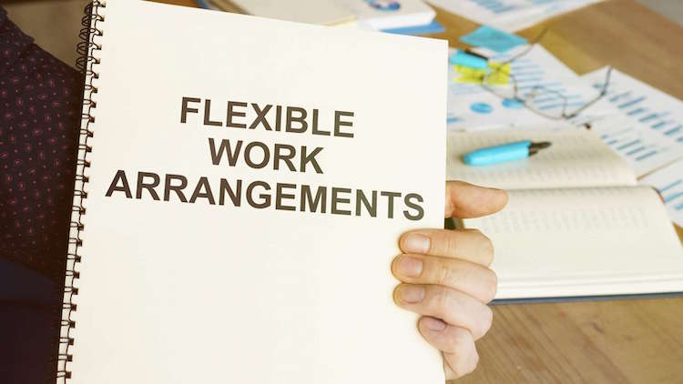 hand holding a notebook that shows the words Flexible Work Arrangements
