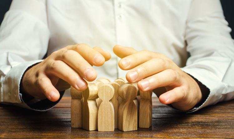 Man covering a group of wooden people