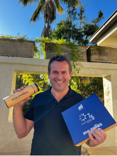 Man holding a wooden tumbler and a blue box