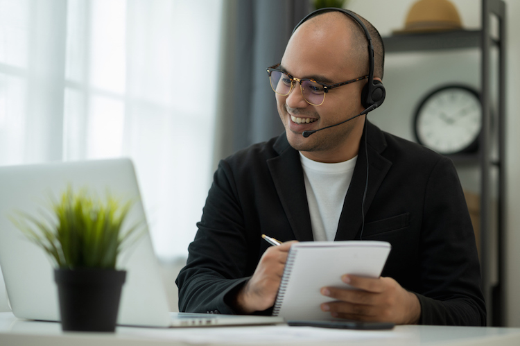 Young asian holding notebook wearing a headset during a video conference