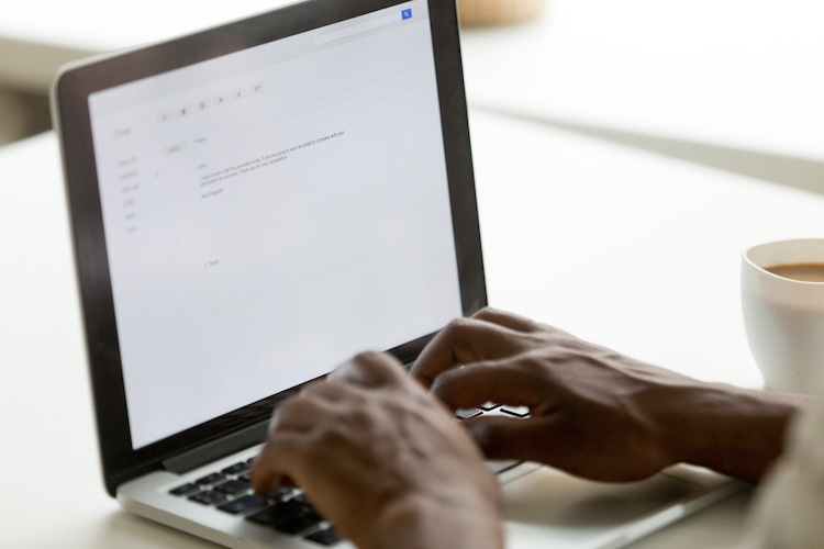 African businessman typing e-mail on laptop using online application