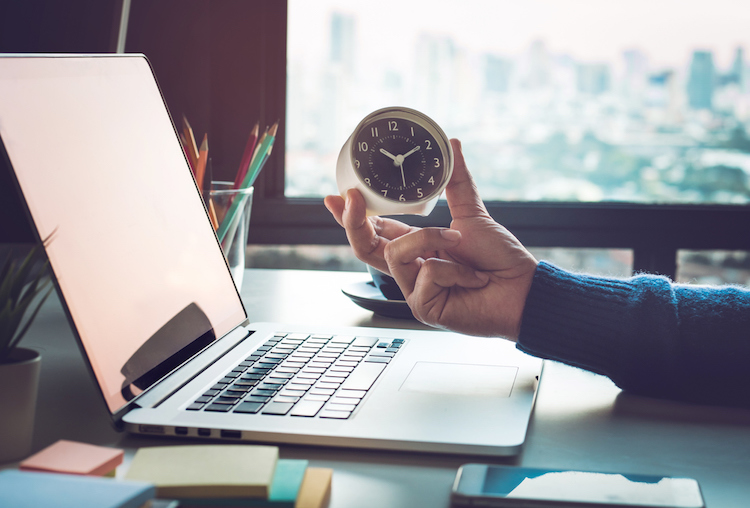 businessman holding clock on computer 