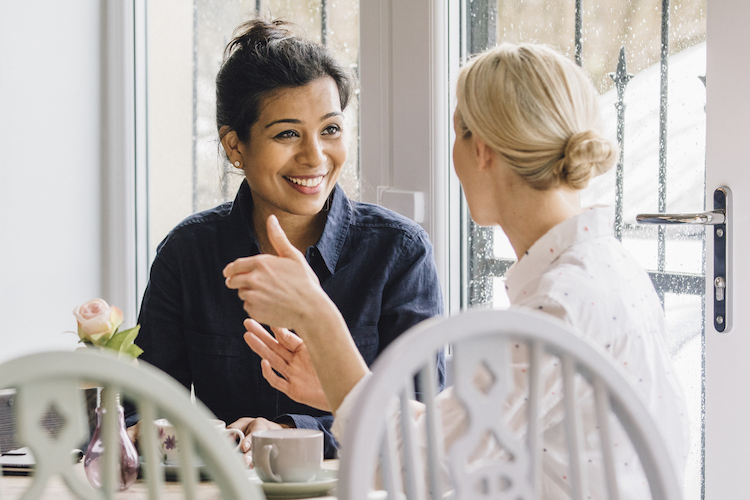 Women are sitting at a table in a cafe, socialising over tea