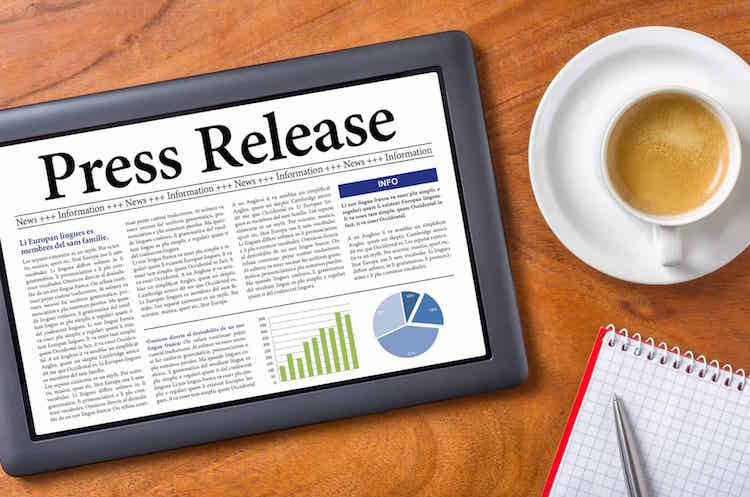 word Press Release on the screen of a tablet next to a cup of coffee