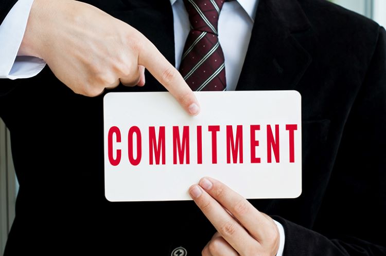 businessman pointing to a sign that says commitment