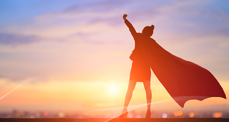 female employee wearing a cape and looking at the sunset