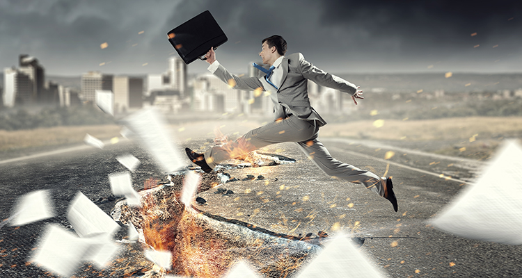 man carrying a briefcase jumping over a huge crack on the road