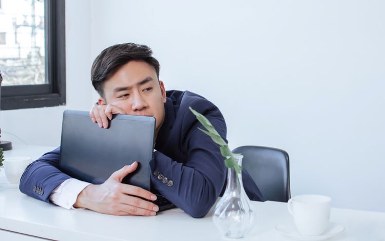 a man wearing a blue suit hugging his laptop