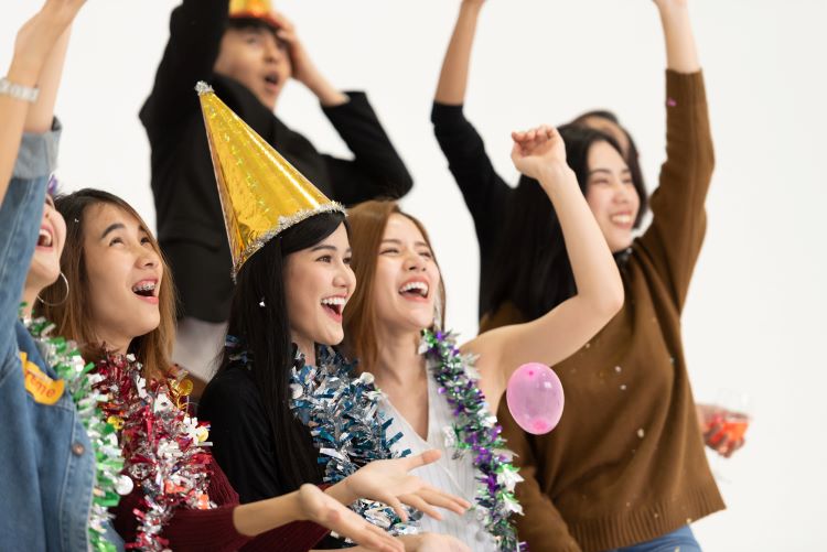 a group of people celebrating with balloons and party hats