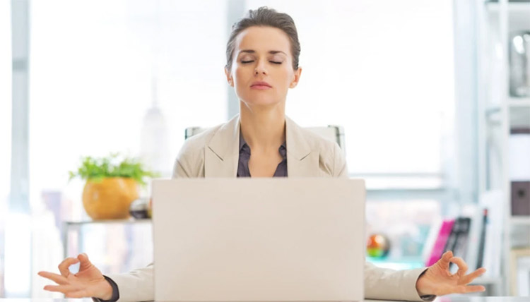 a woman sitting in front of her laptop while her eyes are closed