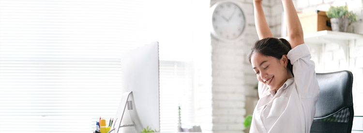 woman at her work desk stretching her arms up