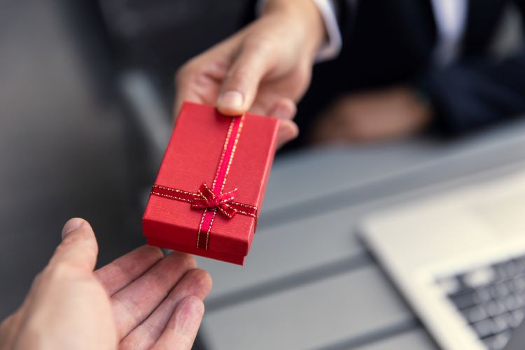 hand passing a red box to another hand