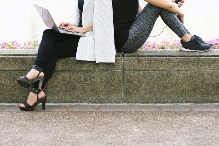 two women sitting back-to-back to each other