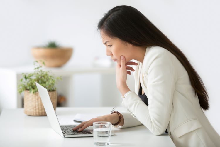 woman in white looking at her screen intently