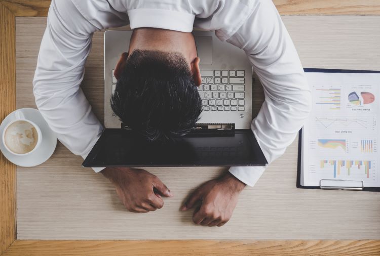 a male employee napping with his head on his laptop's keyboard